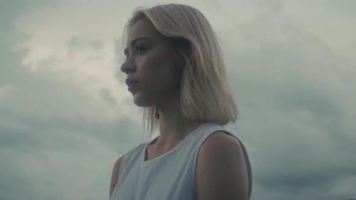 A Woman Immersed in Natures Beauty Under Cloudy Skies Evoking Serenity and Tranquility