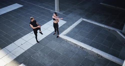 4k video footage of an athletic young couple stretching before embarking on their run in the city