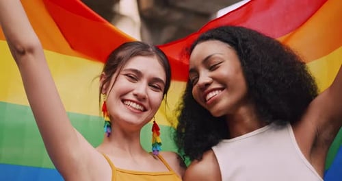 Smiling Young Women Hold Pride Flag Together