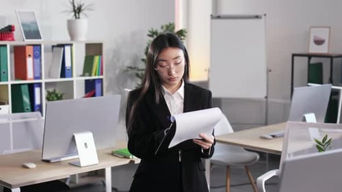 Asian Woman with Clipboard in Hands Standing at Office