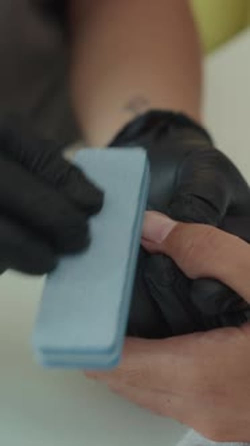 Vertical of Expert Filing Nails of Client in Studio