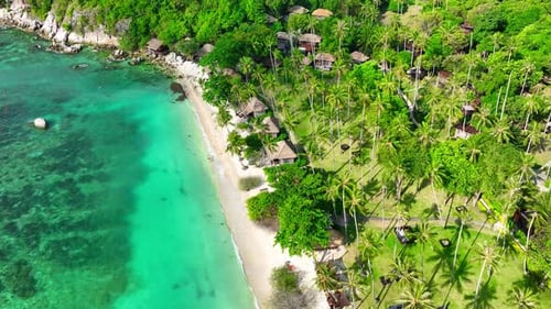 A tropical island with resorts surrounded by clear waters. Drone view.