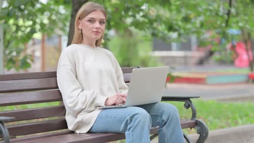 Woman Works on Laptop on Park Bench Outside