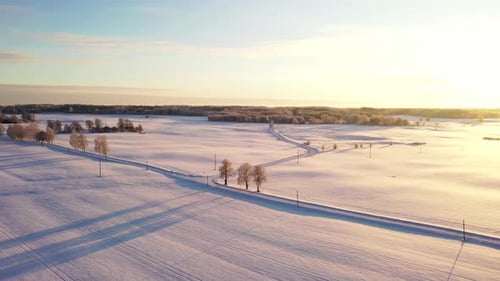 Country side road during cold snowy winter season, golden sunset, aerial drone shot