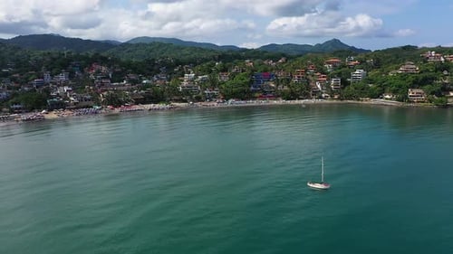 Picturesque Beach Town with Sailboat on Tropical Coast