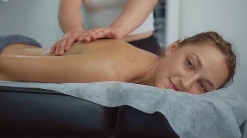 Young Attractive Slim Woman Lying on Massage Table in Spa Center and Enjoying Rejuvenating Back