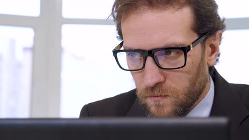 Konzentrierter Geschäftsmann, der intensiv Daten auf dem Laptop-Bildschirm analysiert
