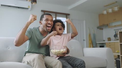 Father and Child Cheering While Watching TV