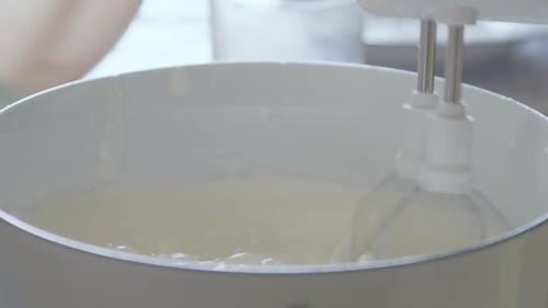 Detail of a cake-making moment: an elderly woman is mixing the ingredients for a cake with electric