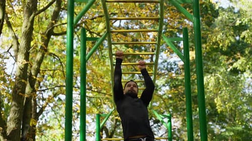 An Athlete Trains on a Horizontal Bar on a Sports Field