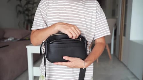 Primer plano de manos naturales y sin cuidado que sostienen una bolsa simple y desgastada que destaca la importancia de
