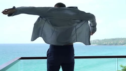 Young Businessman Putting on Shirt on Terrace with Exotic View 30s