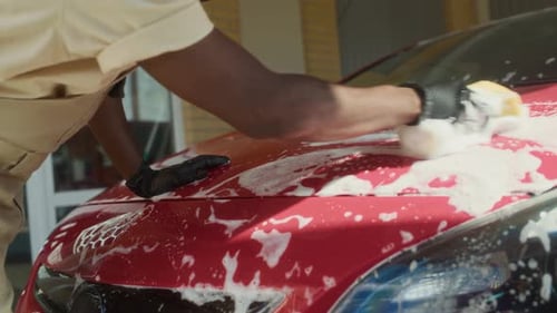 Man Washing Red Car with Soap and Sponge