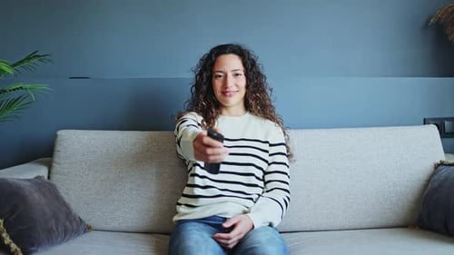Woman Smiling and Holding a TV Remote Control