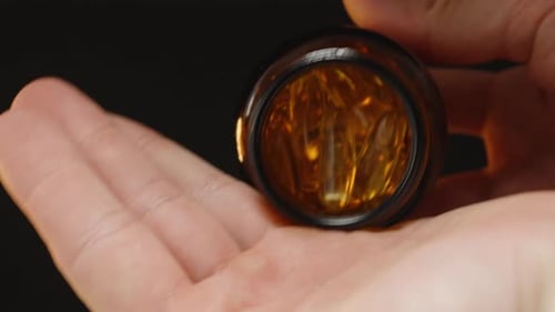 Hand Pours Capsules from Prescription Bottle