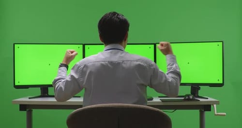 Back View Of Happy Man Celebrating While Working With Mock Up Multiple Monitor In Green Screen