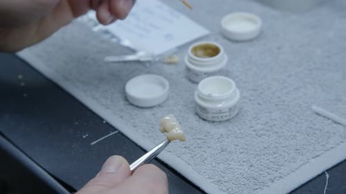 Dental Technician Applies Material to Dental Bridge