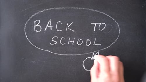 Back to school chalk text appears on a school black board.