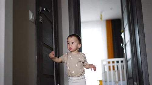 Adorable baby boy stands at the closed door.