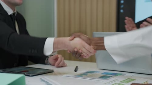 Business Professionals Shake Hands Over Deal Documents