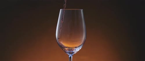 Red Wine Being Poured into Elegant Glass