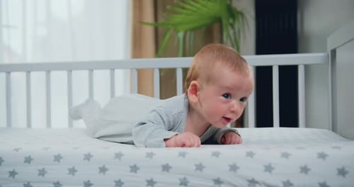 Beautiful blue eyed smiling infant baby portrait close-up. Three month old baby boy lies on his stom