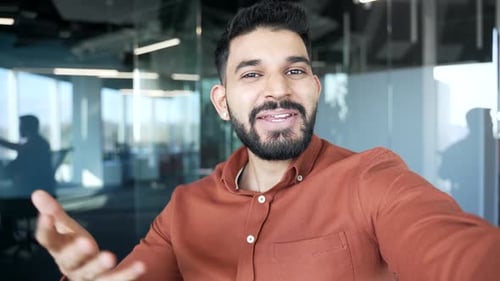 POV Happy businessman talking on a video call using a phone in a modern office. Handsome smiling