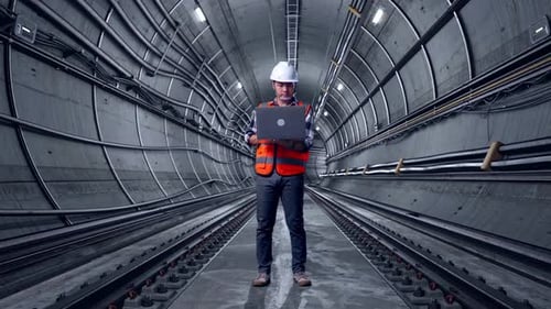 Full Body Of Asian Male Engineer Working On A Laptop In Subway Tunnel