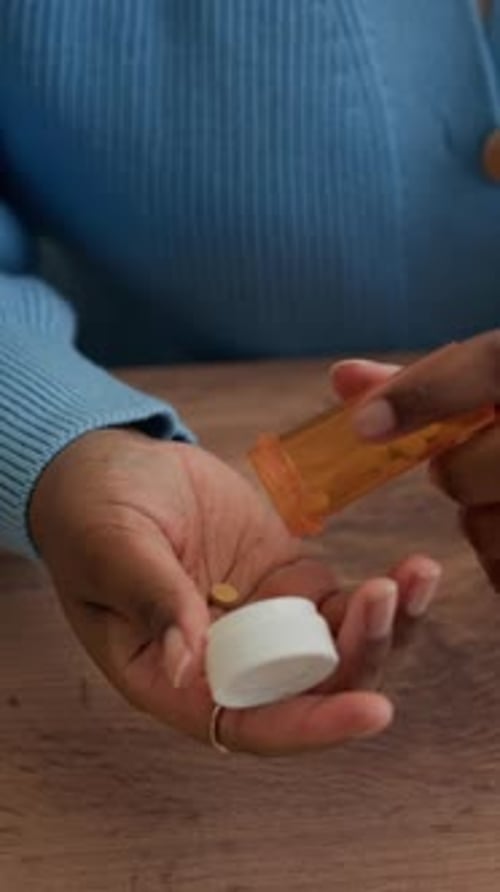 Woman Pours Pills from Bottle onto Hand