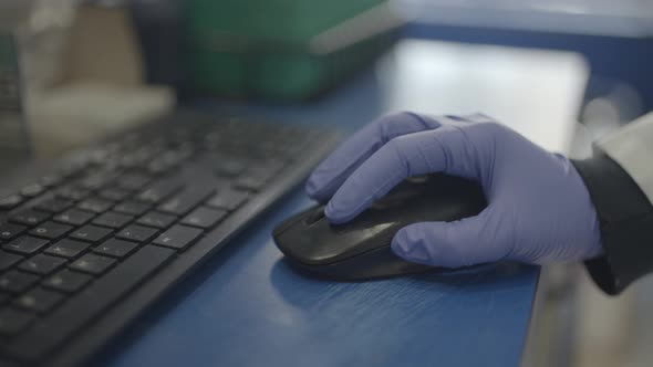 Scientist in lab using mouse for computer research with gloves on hand ...