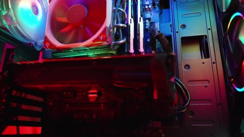 In the darkness, a gaming desktop PC shimmers with rainbow light, close-up of the internal component