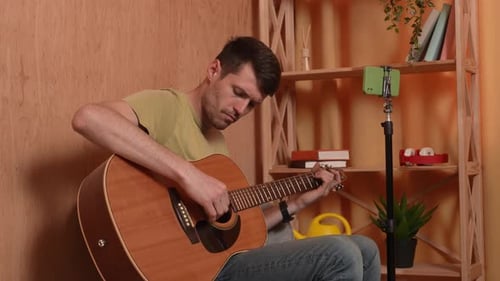 Young Adult Man Playing Acoustic Guitar Indoors