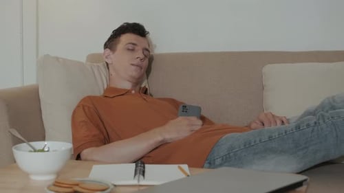Young Adult Relaxing on Couch with Phone