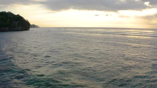 Low flyover Indian Ocean with beautiful small waves and stunning sunset with red orange clouds and s