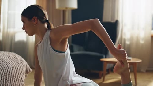 Woman Practices Yoga Stretch at Home