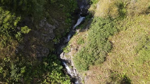 Drone view of the stream flowing through the mountain, water among the greenery