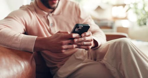 Man using mobile phone on couch in living room