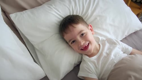 Smiling Child Lying Happily in Bed at Home