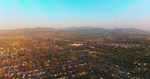 Hot air balloons flying over the beautiful city. Sunlit scenery of Napa, California, USA