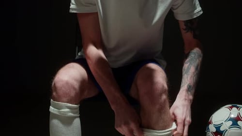 Soccer Player Puts on White Soccer Socks