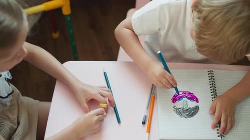Children Drawing Together at Table Indoors