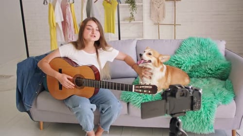 Young Woman Plays Guitar with Corgi at Home