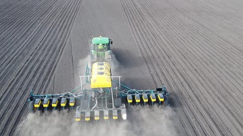 Tractor with yellow seeder working on the field in Ukraine OA Lexa