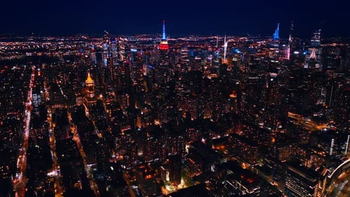 Vast scenery of New York, the USA at night. Tops of skyscrapers are lit with neon light.