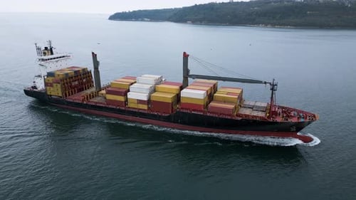 Aerial View of a Large Cargo Ship Loaded with Colorful Containers Sailing Near the Coast Maritime