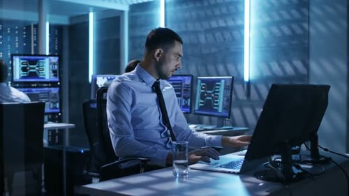 Nahaufnahme eines technischen Ingenieurs, der an seinem Computer mit mehreren Displays im Überwachungsraum arbeitet.
ICH
