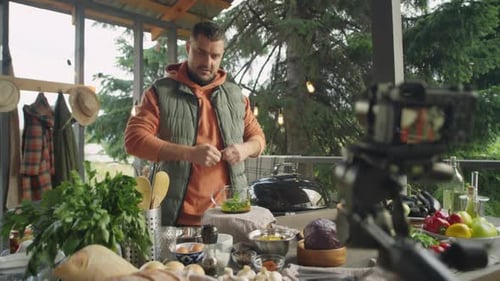 Bloguero gastronómico masculino filma una receta de té en una terraza exterior