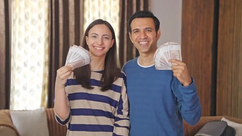 Successful Indian couple using money as fan