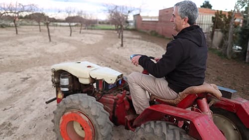 Man Driving Red Tractor Through a Rural Field