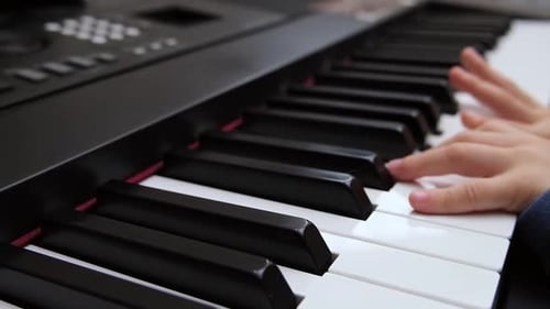 Child Plays Piano Keys with Hands